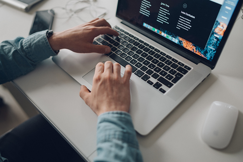 A male's hands poised over a laptop keyboard
